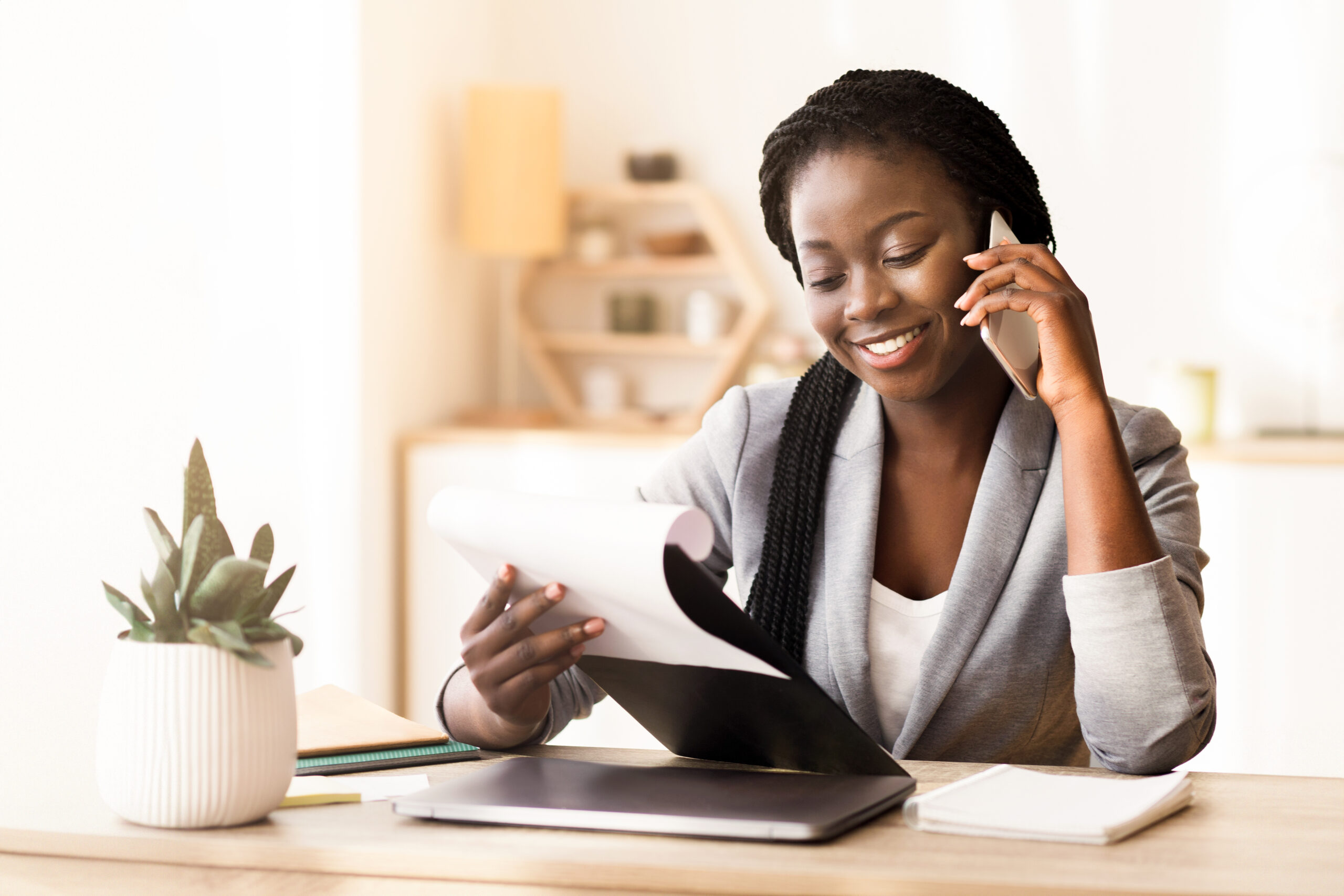 Black female manager making phone call and checking reports in office